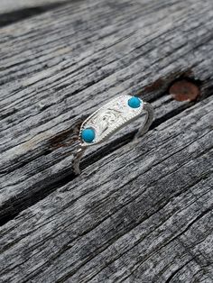 You just found your new go-to turquoise ring: this beautiful little western signet! It features two bright turquoise that frame the intricate hand-engraved details. The ring has a unique feature: a super stylish and cowgirl chic rope band.  Made with love in Eminence, Missouri, this little beauty is perfect for the modern cowgirl who wants a subtle statement piece in her collection.  Check out the white and rose gold version of this ring here.  We make each piece one at a time for every order. Because of this, your final piece may vary slightly from the picture and the engraving style may be adjusted slightly to fit your ring size or customizations. Please allow at least 5 to 6 weeks for shipment. Silver Western Rings, Eminence Missouri, Cowgirl Ring, Silver Pinky Ring, Western Rings, Modern Cowgirl, Diamond Signet Ring, Bright Turquoise, Cowgirl Chic