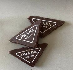 three pieces of chocolate with the words prada and mano written on them are shown