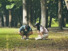 two people kneeling down in the grass near trees