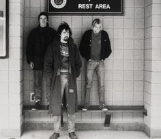 three men standing in front of a rest area sign