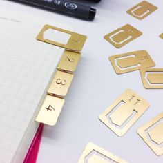 some gold metal pieces are sitting on top of a white sheet of paper next to a marker