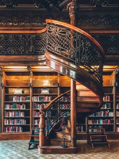 a spiral staircase in front of a bookshelf filled with lots of bookcases