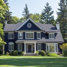 a large blue house with white trim and windows on the front, surrounded by trees