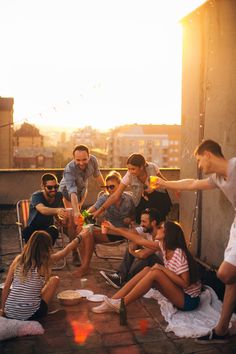 a group of people sitting on top of a roof next to each other holding wine glasses