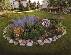 a flower bed in the middle of a yard with rocks and flowers around it,