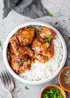 a bowl filled with chicken wings and rice next to two small bowls full of spices