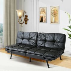 a living room with a black leather couch and potted plant on the wall next to it