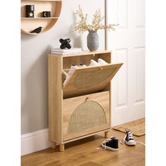 a wooden shelf with shoes on it next to a white wall and a black and white cat