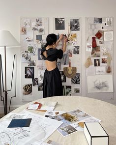 a woman standing in front of a wall covered with pictures and other things on it