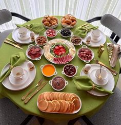 a green table topped with plates and bowls filled with different types of food on top of it