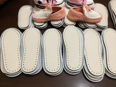 several pairs of baby shoes sitting on top of each other next to pair of foot pads