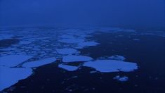 an aerial view of ice floes in the ocean at night with blue hues