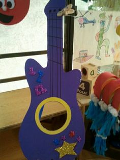 a purple guitar shaped toy sitting on top of a wooden floor next to a window