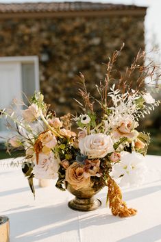 a vase filled with lots of flowers on top of a white table covered in greenery