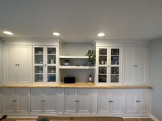 a kitchen with white cabinets and wood flooring, along with built - in shelving