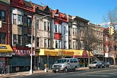 a row of buildings on the side of a street with cars parked in front of them