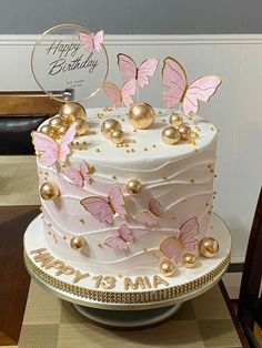 a birthday cake with pink and gold butterflies on it