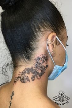 a woman with a tattoo on her neck and behind her ear is wearing a face mask