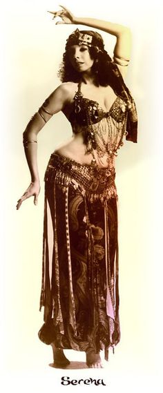 a woman in a belly dance outfit with her hands on her head and arms behind her back