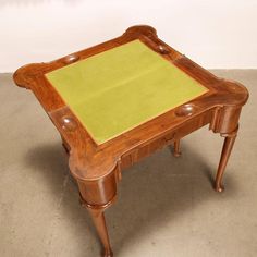 an old wooden table with a green cloth on top