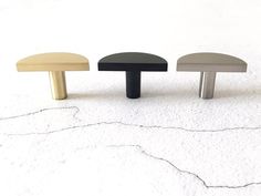 three different colored wooden knobs sitting on top of a white floor next to each other