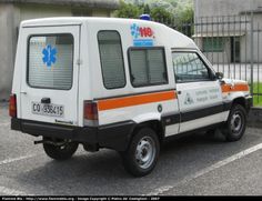 an ambulance parked in a parking lot next to a building with a blue cross on it