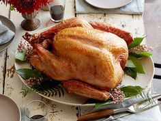 a large turkey sitting on top of a white plate next to other plates and utensils