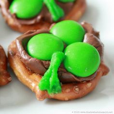 some green and brown donuts are on a white plate with chocolate icing in the shape of shamrocks