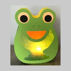 a green frog shaped lamp sitting on top of a wooden table