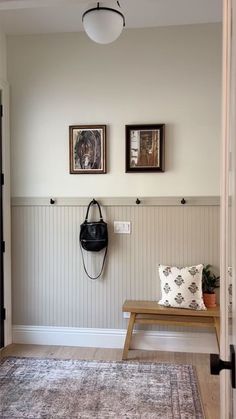 a hallway with a bench and two pictures on the wall above it, along with an area rug