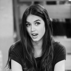 a woman with long hair sitting down and making a funny face while looking at the camera