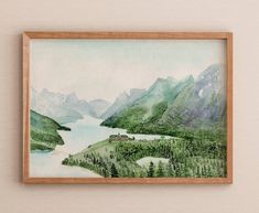 a painting hanging on the wall above a wooden frame with a lake and mountains in the background