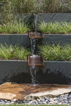 a water fountain in the middle of a garden with grass growing on it's sides