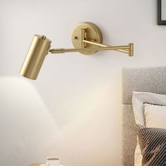 a lamp that is on the side of a wall next to a bed with pillows