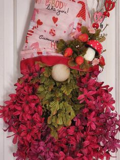 a door hanger decorated with red flowers and a stuffed animal in the center,