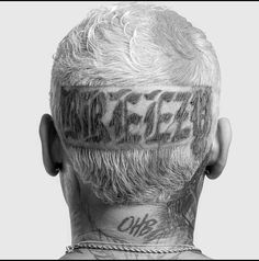 the back of a man's head with tattoos and words on his foreheads