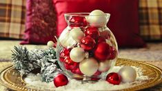 a glass vase filled with red and white ornaments on top of snow covered ground next to pillows