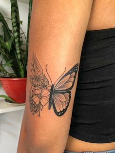 a woman's arm with a butterfly and flowers tattoo on the left side of her arm