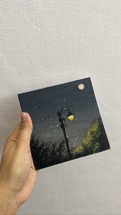 a hand holding up a card with a street light in the night sky above it