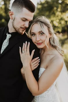 a bride and groom embracing each other in front of some trees at their wedding day