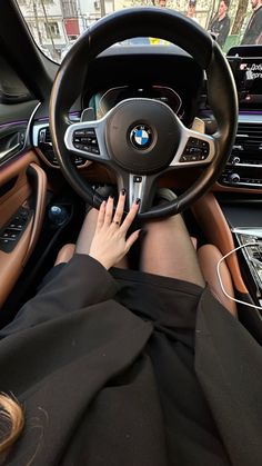 a woman is sitting in the driver's seat of a car with her hands on the steering wheel