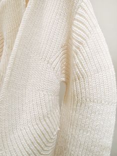 a white sweater hanging up on a rack