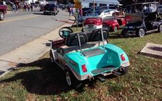 an old blue car is parked on the side of the road in front of other cars