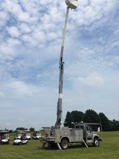 a utility truck is parked next to a light pole in the middle of a field