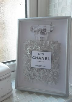 a chanel perfume bottle sitting on top of a window sill next to a white box