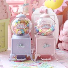 two gummy machines sitting next to each other on top of a pink tablecloth