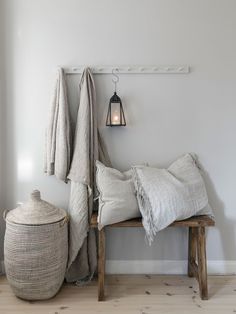 a bench with pillows and blankets on it next to a light hanging from the wall