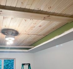 an empty room with a ceiling fan and window in the corner, next to a ladder