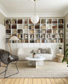 a living room filled with lots of bookshelves next to a white couch and coffee table