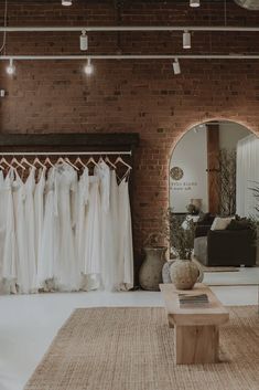 the bridal gowns are on display in this room with brick walls and flooring